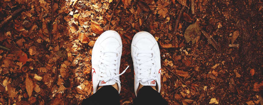 Feet with trainers on autumn leaves